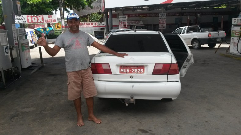 Nivaldo com os pés descalços no posto de gasolina